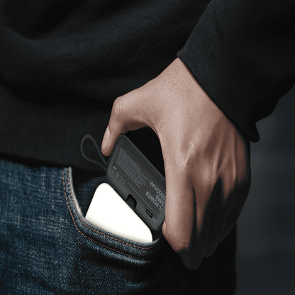 Hand inserting a smartphone into a pocket with a dark background