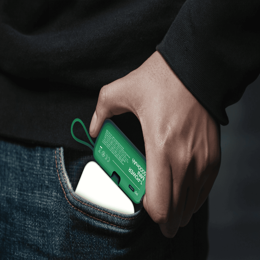 Hand inserting a green and white device into a pocket against a dark background