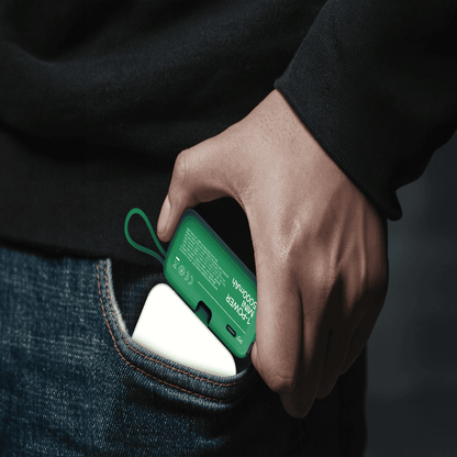 Hand inserting a green and white device into a pocket against a dark background