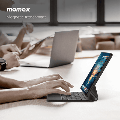 Person using a tablet with a keyboard attachment in an office setting, featuring Momax branding.
