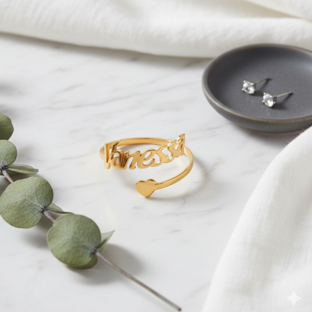 Gold ring with 'Fiancee' on a white surface with greenery and earrings in the background