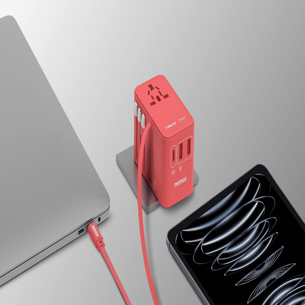 Red power adapter with multiple outlets next to a laptop and smartphone on a light gray background