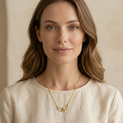 Woman wearing a gold necklace with a beige background