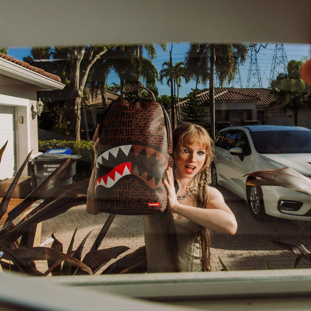 Person holding a shark-patterned bag in front of a car window with a suburban background