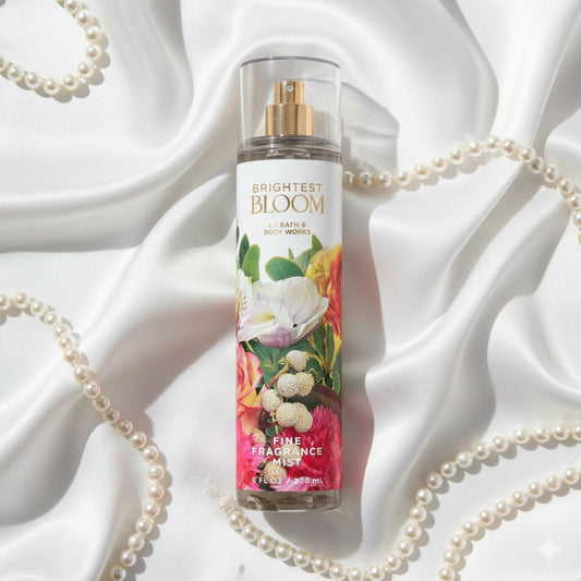 Bottle of 'Brightest Bloom' fine fragrance mist on a white fabric background with pearls.
