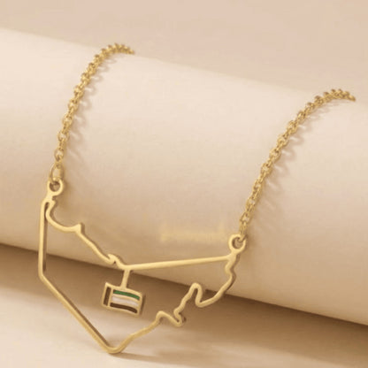 Gold necklace with a map design and small flag pendant on a beige background