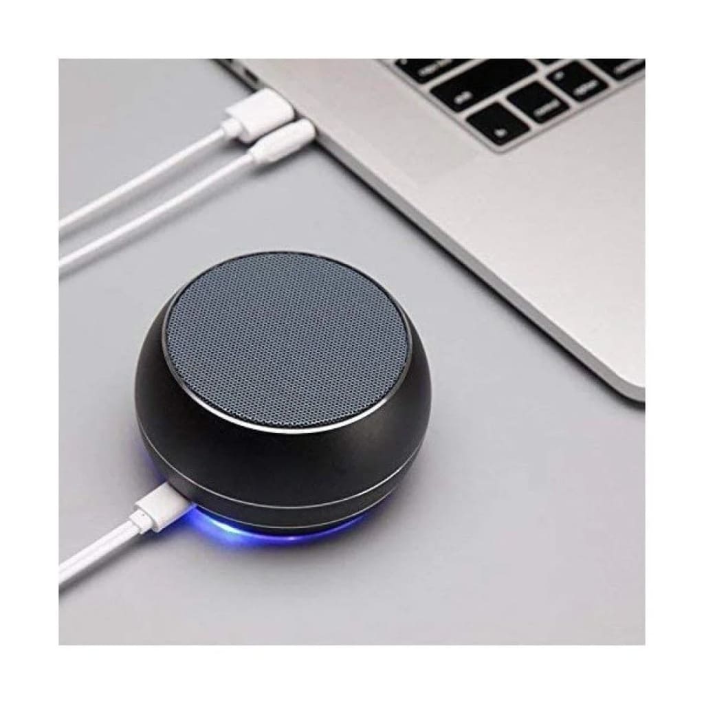 Black wireless charging pad with blue light on a desk next to a laptop.