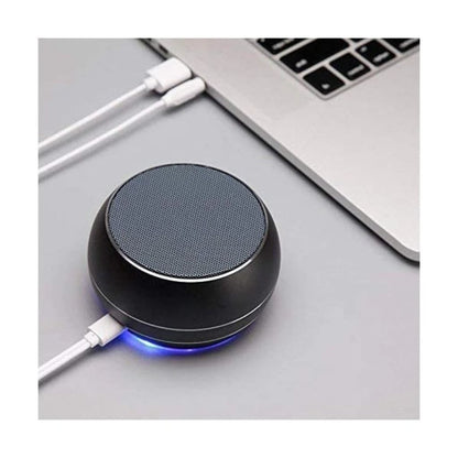 Black wireless charging pad with blue light on a desk next to a laptop.